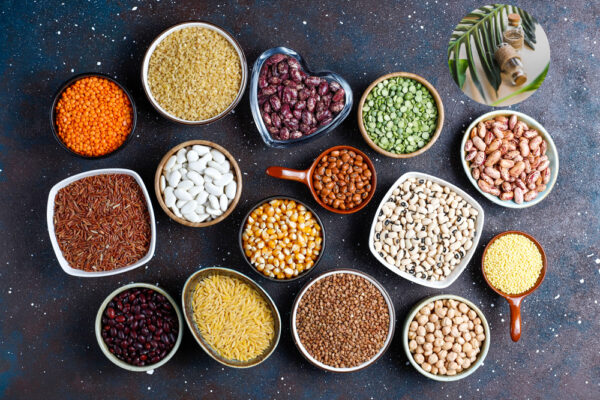 Legumes and beans assortment in different bowls on light stone b
